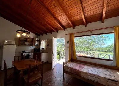 a kitchen and dining room with a table and a large window at La Rabona Cabañas in Las Rabonas