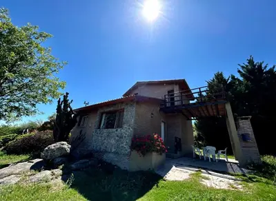 a house on a hill with the sun in the sky at La Rabona Cabañas in Las Rabonas
