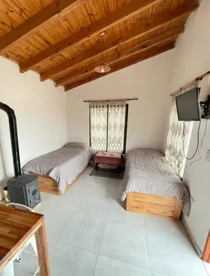 two beds in a room with a tv and a tv at Caminito in Los Reartes