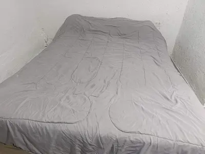 a bed is covered with a gray comforter at Departamento nubes in Cordoba
