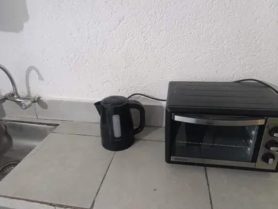 a black coffee pot sitting next to a toaster oven at Departamento nubes in Cordoba