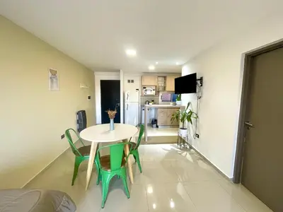 a room with a table and chairs and a kitchen at Nova Urbs in Cordoba