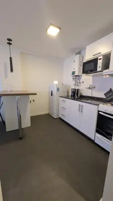 a large kitchen with white cabinets and a table at Apartamento de un dormitorio, Nueva Córdoba in Cordoba