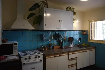 a kitchen with white cabinets and blue tile on the wall at La casa de Mirta Habitaciones en Córdoba in Cordoba