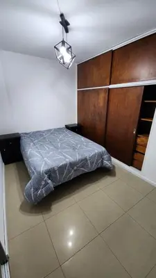 a bedroom with a bed and a wooden cabinet at Depto San Martín VCP in Villa Carlos Paz