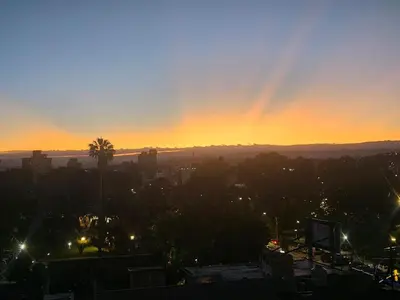 a rainbow in the sky over a city at sunset at Depto San Martín VCP in Villa Carlos Paz