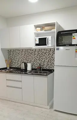 a white kitchen with a microwave and a refrigerator at Sam Gabrielll in Villa Carlos Paz