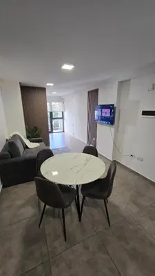 a living room with a table and chairs and a couch at Dpto NVA CBA calle OBISPO TREJO con PILETA y QUINCHO in Cordoba