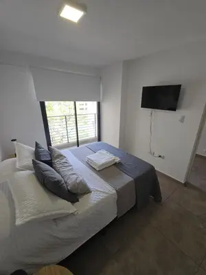 a bedroom with a bed with pillows and a television at Dpto NVA CBA calle OBISPO TREJO con PILETA y QUINCHO in Cordoba