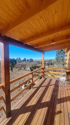 a wooden deck with a table and a chair on it at Entre Sierras y Sueños in Villa Yacanto