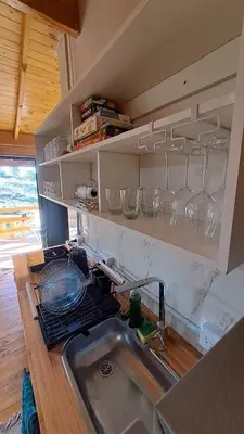a kitchen with a sink and glasses on the shelves at Entre Sierras y Sueños in Villa Yacanto