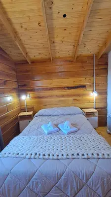 a bed in a wooden room with two towels on it at Entre Sierras y Sueños in Villa Yacanto