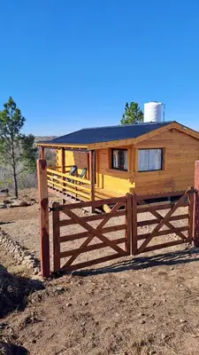 a wooden house with a fence in front of it at Entre Sierras y Sueños in Villa Yacanto