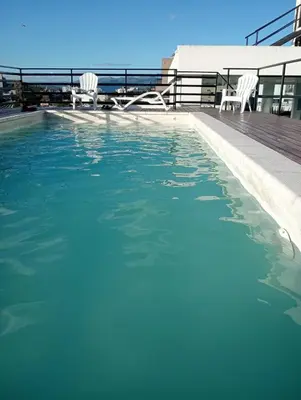a swimming pool with two chairs in the water at Departamento Carlos Paz Paseo Quattro 36 Cochera Piscina Céntrico in Villa Carlos Paz