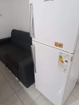 a white refrigerator in a room with a black couch at Departamento tolosa in Cordoba