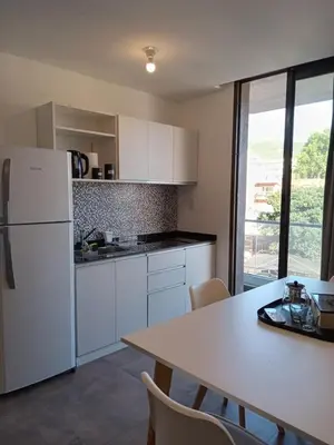 a kitchen with a white refrigerator and a table with chairs at Sam Lake 3 in Villa Carlos Paz