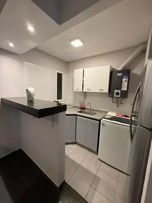 a kitchen with white cabinets and a black counter top at Amplio, luminoso y cerca de todo! in Cordoba