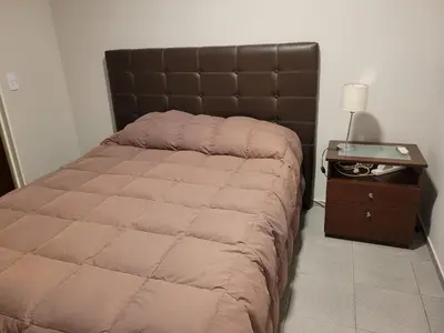 a bed in a bedroom with a nightstand and a bed sidx sidx at Amplio, luminoso y cerca de todo! in Cordoba
