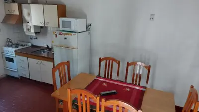 a kitchen with a wooden table and a white refrigerator at Castillo Del Lago - Carlos Paz - D18 in Villa Carlos Paz