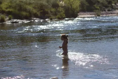 a little girl standing in the water in a river at Apartamento por día Cuesta Blanca in Cuesta Blanca