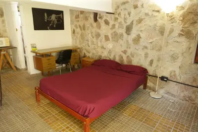a bedroom with a red bed in a stone wall at Apartamento por día Cuesta Blanca in Cuesta Blanca