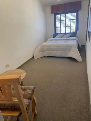 a bedroom with two beds and a table and a window at Casa de Gregorio Hostel in Cordoba
