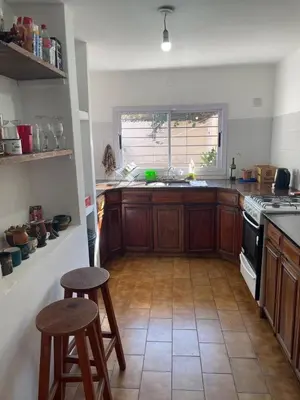 a kitchen with wooden cabinets and two stools in it at Casa de Gregorio Hostel in Cordoba