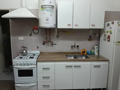 a kitchen with white cabinets and a stove and a sink at Casa ideal Pileta, Quincho y Patio Enorme in Bialet Massé