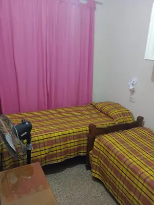 two beds in a room with purple curtains at Casa ideal Pileta, Quincho y Patio Enorme in Bialet Massé