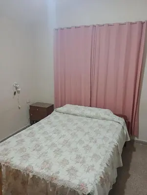 a bedroom with a bed with a pink curtain at Casa ideal Pileta, Quincho y Patio Enorme in Bialet Massé