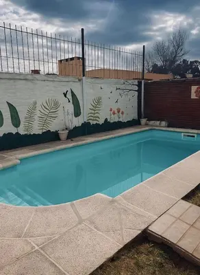 a swimming pool in front of a wall with a mural at Casa completa con pileta y asador, a metros del lago in Villa Carlos Paz