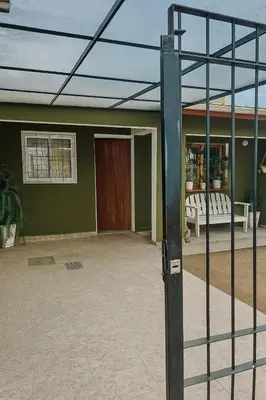 a green building with a door and a fence at Casa completa con pileta y asador, a metros del lago in Villa Carlos Paz