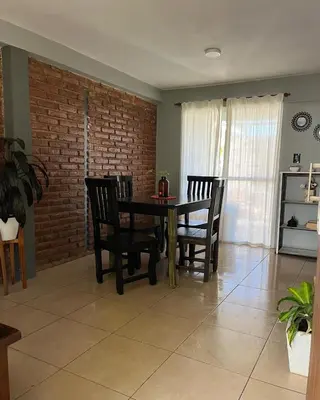 a dining room with a table and chairs and a brick wall at Casa completa con pileta y asador, a metros del lago in Villa Carlos Paz