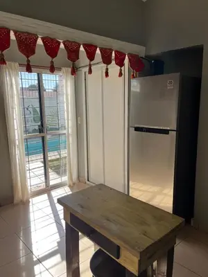 a kitchen with a wooden table and a refrigerator at Casa completa con pileta y asador, a metros del lago in Villa Carlos Paz