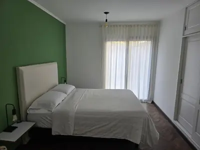 a bedroom with a white bed and a green wall at ByB ALQUILERES 3 in Cordoba