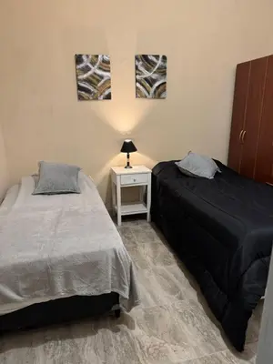 a bedroom with two beds and a night stand with a lamp at Apart Suipacha in Río Cuarto