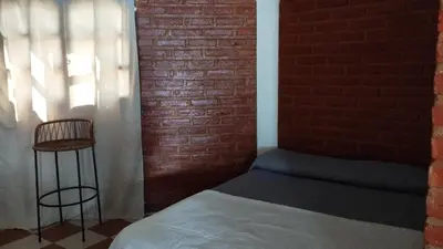 a bedroom with a bed and a brick wall at Departamento en Nono Descanso y aventura in Nono