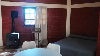 a bedroom with a bed and chairs and a window at Departamento en Nono Descanso y aventura in Nono