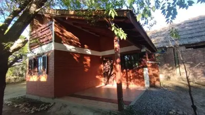 a brick house with a porch and a tree at Acogedora cabaña en el corazón de Nono in Nono
