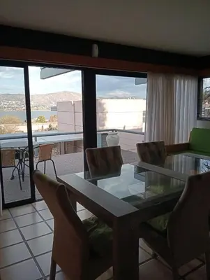 a dining room with a glass table and chairs at Casa Carlos Paz Terrazas del Lago in Villa Carlos Paz