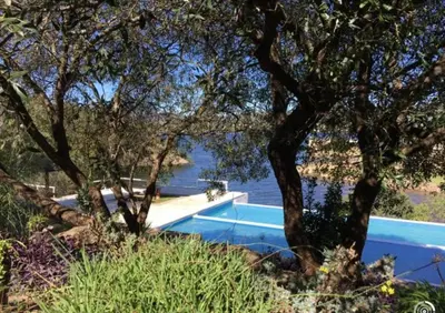 a swimming pool next to a body of water with trees at Casa Carlos Paz Terrazas del Lago in Villa Carlos Paz