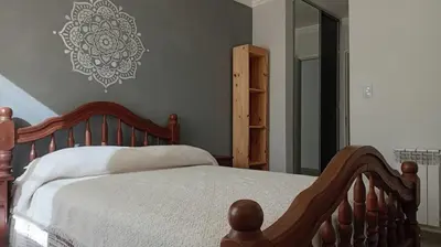 a bedroom with a wooden bed and a mirror at Exelente departamento en Carlos Paz in Villa Carlos Paz