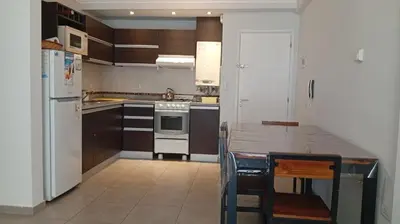 a kitchen with wooden cabinets and a white refrigerator at Exelente departamento en Carlos Paz in Villa Carlos Paz