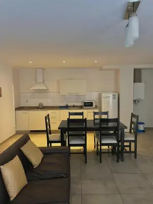 a living room with a table and chairs and a kitchen at Central Suites Hotel in Villa Carlos Paz
