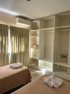 a bedroom with two beds and shelves and a window at Central Suites Hotel in Villa Carlos Paz