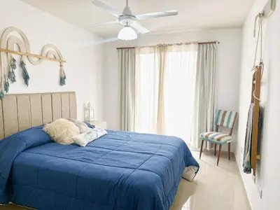 a bedroom with a blue bed with a ceiling fan at OPERA Apartamentos in Villa Carlos Paz