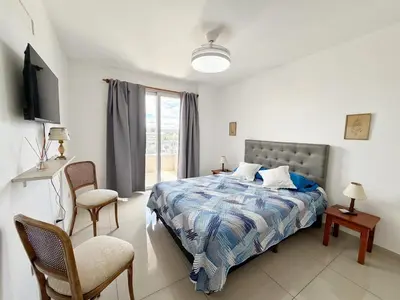 a bedroom with a bed and two chairs and a television at OPERA Apartamentos in Villa Carlos Paz