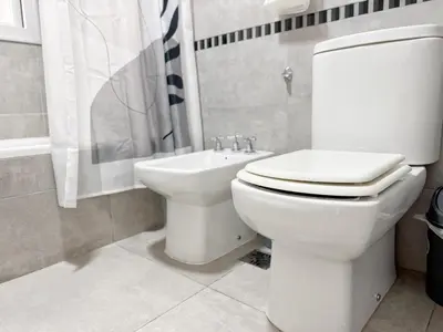 a white bathroom with a toilet and a sink at OPERA Apartamentos in Villa Carlos Paz