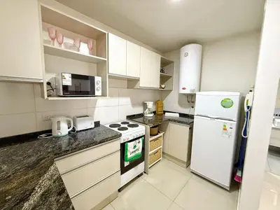 a kitchen with a white refrigerator and a stove at OPERA Apartamentos in Villa Carlos Paz