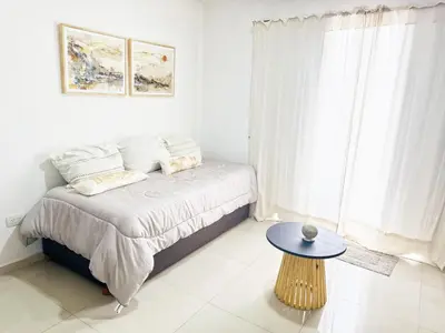 a bedroom with a bed with a table and a window at OPERA Apartamentos in Villa Carlos Paz